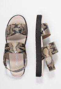 Ruskeat ja mustat tekonahkaiset käärmeennahkakuosisandaalit, joissa on kaksi leveää hihnaa ja takahihna. Sandaaleissa on pehmustettu pohja ja musta kumipohja.