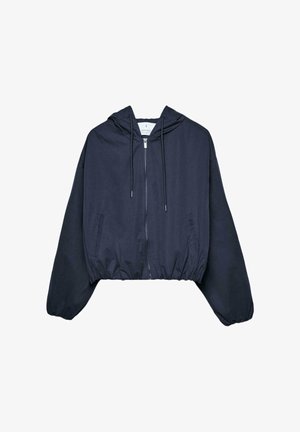 Giacca corta con cappuccio blu navy con cerniera frontale, cappuccio con coulisse, orlo elastico e tasche laterali su sfondo bianco.