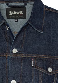 Veste en denim, bleu foncé avec des coutures orange. Dispose d'un col pointu, de boutons sur le devant et d'une étiquette de marque sur la poche gauche. Taille M.