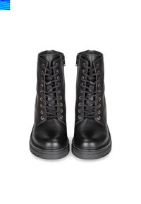 Botas de cuero negro con un acabado texturizado, que cuentan con ojales metálicos, cordones negros, una suela gruesa y cremalleras laterales para facilitar su uso.