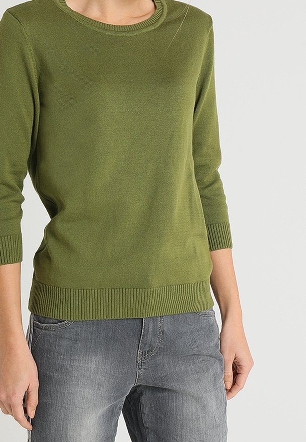 Grüner, gestrickter Pullover mit rundem Halsausschnitt und dreiviertellangen Ärmeln. Gerippte Bündchen und Saum; getragen mit grauen Denim-Hosen.