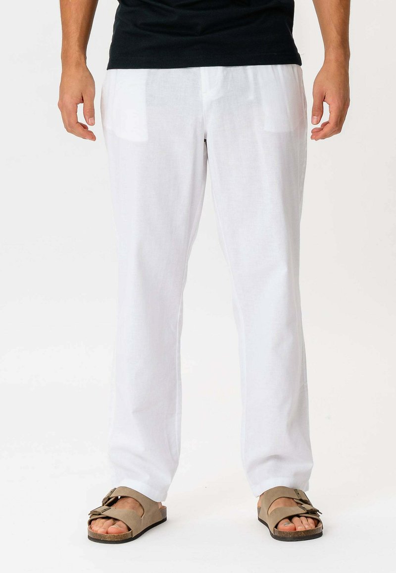 Hvide linnedbukser med et afslappet fit, der har to frontlommer, og som er parret med brune slidesandaler. Glat tekstur, letvægtsdesign.