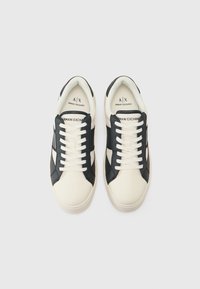 Hvite og marineblå lær sneakers med kontrastpaneler, hvite snørebånd og en glatt tekstur. Merkevare synlig på tungen og innersålen.