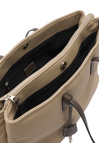Beżowa torebka z dwoma głównymi przegrodami, jedna zamykana na suwak, a druga na zatrzask magnetyczny, z ciemnym wnętrzem i uchwytami.