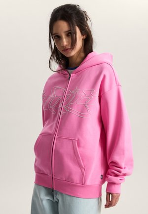 Pink zip-up hoodie made of soft fabric with a large rhinestone graphic. Features a kangaroo pocket and ribbed cuffs at the sleeves and hem.