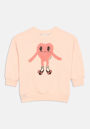 Sweatshirt rosa com um gráfico de personagem em forma de coração peludo, apresentando olhos grandes e membros. Punhos e bainha com detalhes de design em contraste.