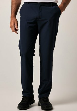 Navyfarbene Polyesterhosen mit geraden Beinen, ausgestattet mit Seitentaschen und einer glatten Textur. Kombiniert mit schwarzen Sportschuhen.