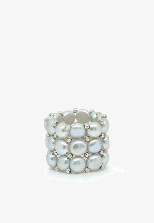 Large bague composée de trois rangées de perles blanches rondes reliées par de petites perles argentées sur un fond blanc.