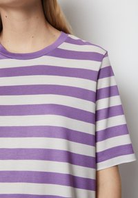 Purple and white striped short-sleeve t-shirt with a round neckline, made from soft cotton fabric. The stripes are evenly spaced.