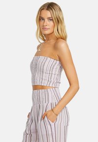 Ärmelloses Crop-Top in Helllila mit vertikalen, mehrfarbigen Streifen und gerafftem Textur, kombiniert mit hoch taillierten, gestreiften, weit geschnittenen Hosen.