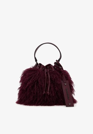 Sac seau bordeaux duveteux avec fermeture à cordon, courte bandoulière en cuir et étiquette rectangulaire en cuir attachée avec des clous métalliques.