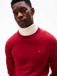 Maglione rosso a maglia con collo a girocollo a coste, dotato di un colletto bianco a lupetto sotto. Piccolo logo ricamato sul petto, texture liscia.