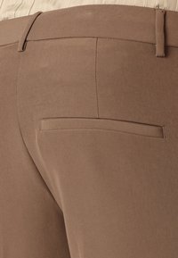 Brown trousers with a smooth texture, featuring a flat back pocket and a tailored waistband. Clean lines and minimal design accents are visible.