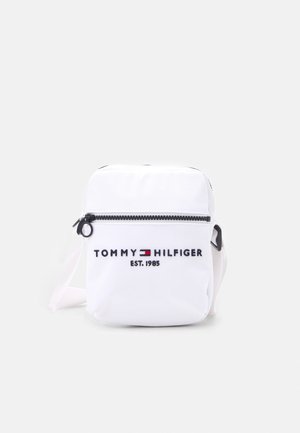 Petit sac bandoulière blanc avec fermeture éclair noire, logo Tommy Hilfiger et texte "EST. 1985" à l'avant.