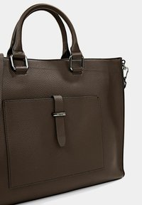 Brun läderhandväska med pebble-yta, två handtag upptill, en framficka och silverdetaljer. Slät textur och rektangulär form.