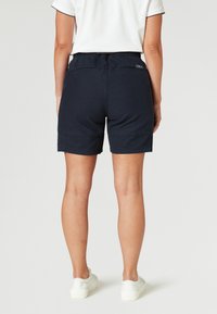 Marineblauwe shorts van lichtgewicht stof, met een relaxte pasvorm, elastische tailleband en stikselsdetails. Eenvoudig ontwerp zonder patronen.