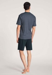 Marineblauwe en witte gestreepte T-shirt met korte mouwen, gecombineerd met donkergroene shorts, ontworpen voor comfort met een relaxte pasvorm en zachte stof.