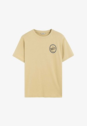 T-shirt en coton jaune avec des manches courtes et un col rond, arborant un logo rond marine sur la partie gauche de la poitrine. Texture douce et lisse.