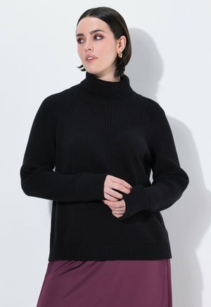 Czarny sweter z golfem o prążkowanej fakturze i wzorze w zygzak na piersi. Posiada długie rękawy i luźny krój.