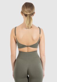 Sujetador bralette verde oliva con tirantes ajustables, textura suave y diseño de espalda cruzada, combinado con leggings de talle alto a juego.