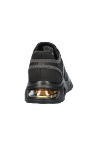 Zwarte sportieve schoen met een textiel bovenwerk, gevoerde hielband en zichtbare luchtkussensole, met een strakke, moderne uitstraling.