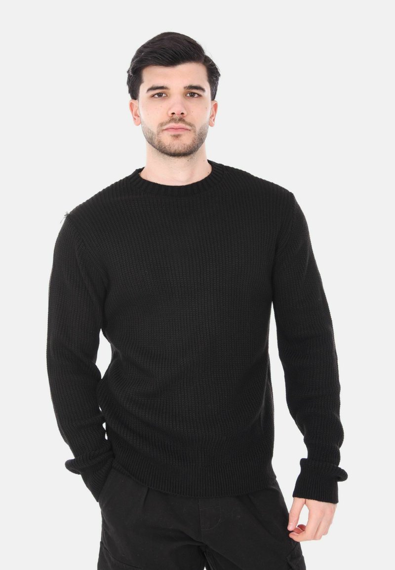 Maglione nero lavorato a maglia con scollo rotondo, texture a coste e maniche lunghe. Presenta una vestibilità rilassata e polsini che si estendono sulle mani.
