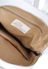 Borsa in pelle bianca aperta per mostrare l'interno in tessuto beige con tasca con zip e etichetta in pelle "Made in Italy" all'interno.