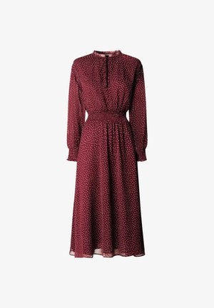 Vestido burdeos de manga larga con cintura fruncida, con un escote alto y lunares blancos, confeccionado en una tela ligera y fluida.