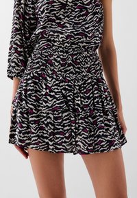Gonna da donna con un cintura arricciata, volant sovrapposti e una stampa a strisce zebrate nera, bianca e rosa su un tessuto leggero.