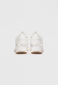 Pair of white platform sneakers shown from the back with a silver accent strip and branding on the heel.