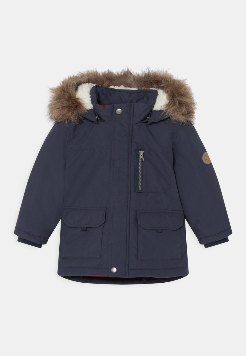 Granatowa parka z kapturem wyłożonym futrem, dwoma przednimi kieszeniami, zamykaną na zamek kieszenią na piersi oraz ściągaczami przy mankietach. Posiada czerwone wykończenie wewnętrzne.