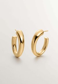 Pendientes de aro de oro con una superficie lisa y pulida; diseño redondeado con un perfil grueso y postes roscados para el cierre, sobre un fondo neutro.