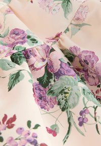 Mīksta rozā auduma ar ziedu rakstu purpura nokrāsās, zaļām lapām un maziem ogu ķekariem, ar savāktiem krokām.