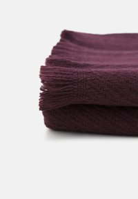 Cachecol de malha cor burgundy, dobrado, exibindo um padrão texturizado com bordas frisadas. Material suave, aparência quente e forma retangular.
