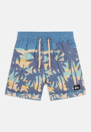 Costume da bagno blu con stampa di palme gialle e verdi. Vita elastica con cordino rosa chiaro. Include una toppa con logo.