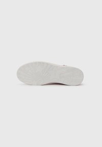 White sneaker sole with intricate star and sunburst patterns. Textured rubber for grip, slightly rounded edges. Clean, minimal design.