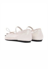 Bailarinas de malla blanca con un tacón de cuero liso, cinta elástica y un lazo decorativo. La malla texturizada contrasta con un panel trasero sólido.