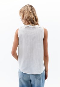 Ärmellose, hellgraue Bluse mit gerippter Textur und einem runden Kragen. Verfügt über vertikale Streifen und einen abgerundeten Saum im Rücken.