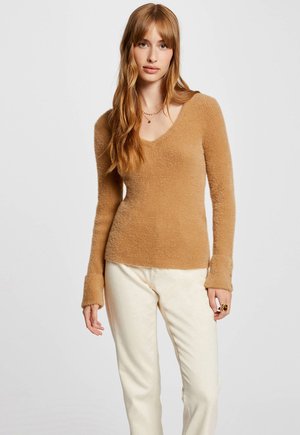 Maglione beige chiaro con scollo a V, dal finish morbido e texturizzato, e maniche lunghe. Abbinato a pantaloni beige chiaro, con vestibilità comoda e dettagli discreti.
