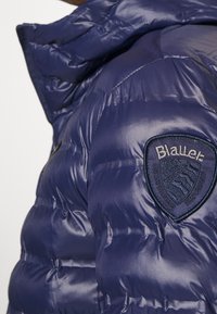 Giubbotto trapuntato lucido blu navy con un patch del logo Blauer sulla parte superiore del braccio e un collo alto.