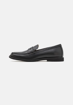 Mocassin noir en cuir pour homme avec un petit talon et des détails perforés le long du bord supérieur, vu de côté sur fond blanc.