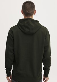 Felpa verde con cappuccio e cordino, dotata di tasca a marsupio. Materiale morbido in misto cotone. Presenta polsini e orlo a coste per una vestibilità aderente.
