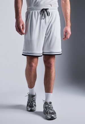 Hvide mesh atletik shorts med sorte detaljer, elastisk talje og snører. Kombineret med grå sneakers og hvide ankelstrømper.