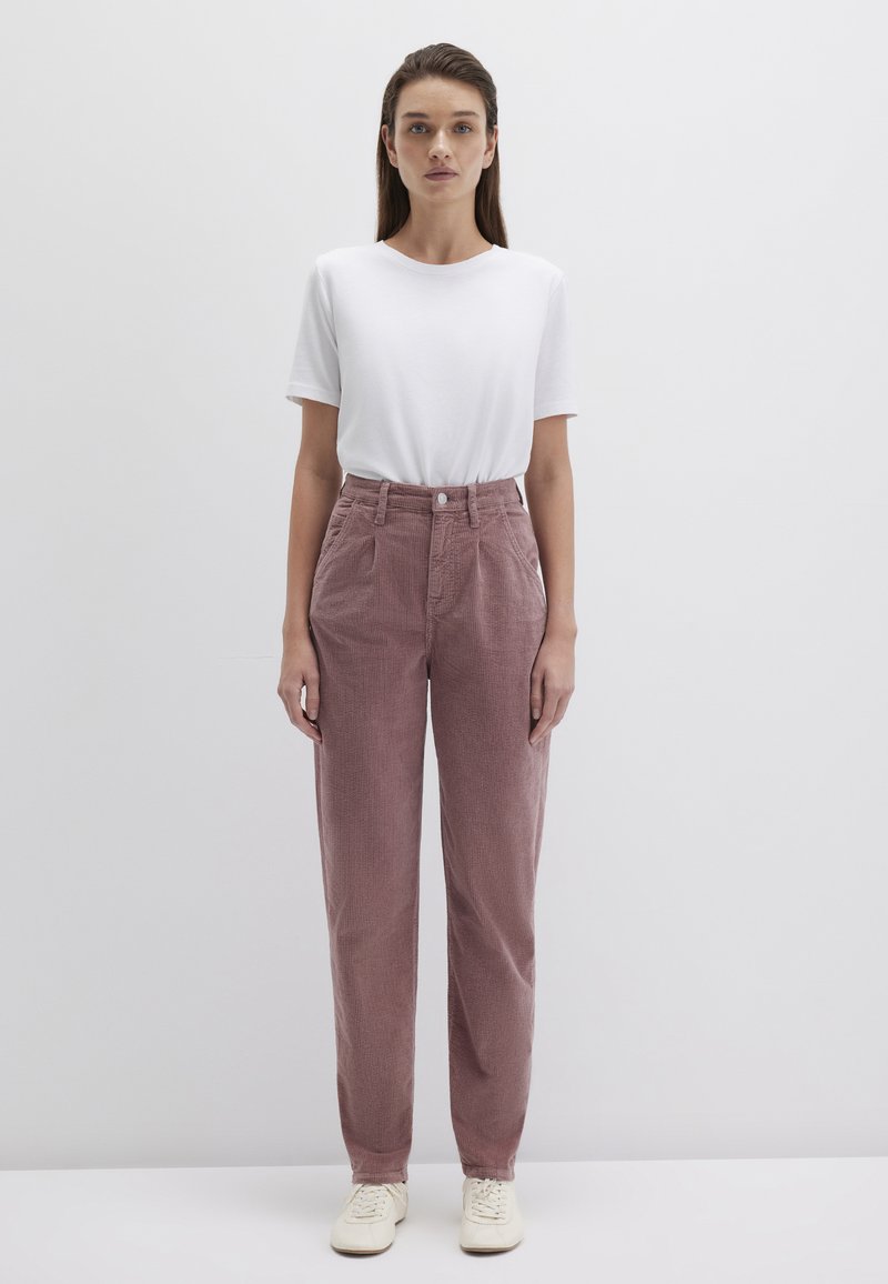 Hellrosa Cordhose mit hoher Taille und geradem Bein, kombiniert mit einem schlichten weißen T-Shirt und beigen Sneakern, auf einem neutralen Hintergrund präsentiert.