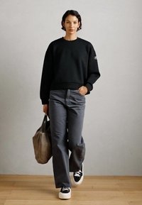 Felpe nere, pantaloni palazzo grigi, sneakers bianco e nere, e una borsa a tracolla grigia chiara. Design semplice senza motivi o accessori distintivi.