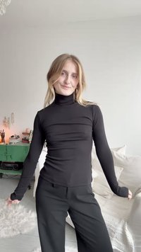 Čierny rolák vyrobený z elastického materiálu, priliehavý strih, dlhé rukávy s priechodmi na palce, skombinovaný s voľnými čiernymi nohavicami, minimalistický štýl.