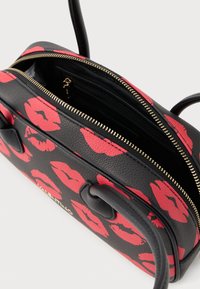 Borsa in pelle nera con stampa di labbra rosse, chiusura con cerniera dorata e due manici neri. L'interno presenta più scomparti per un'organizzazione ottimale.