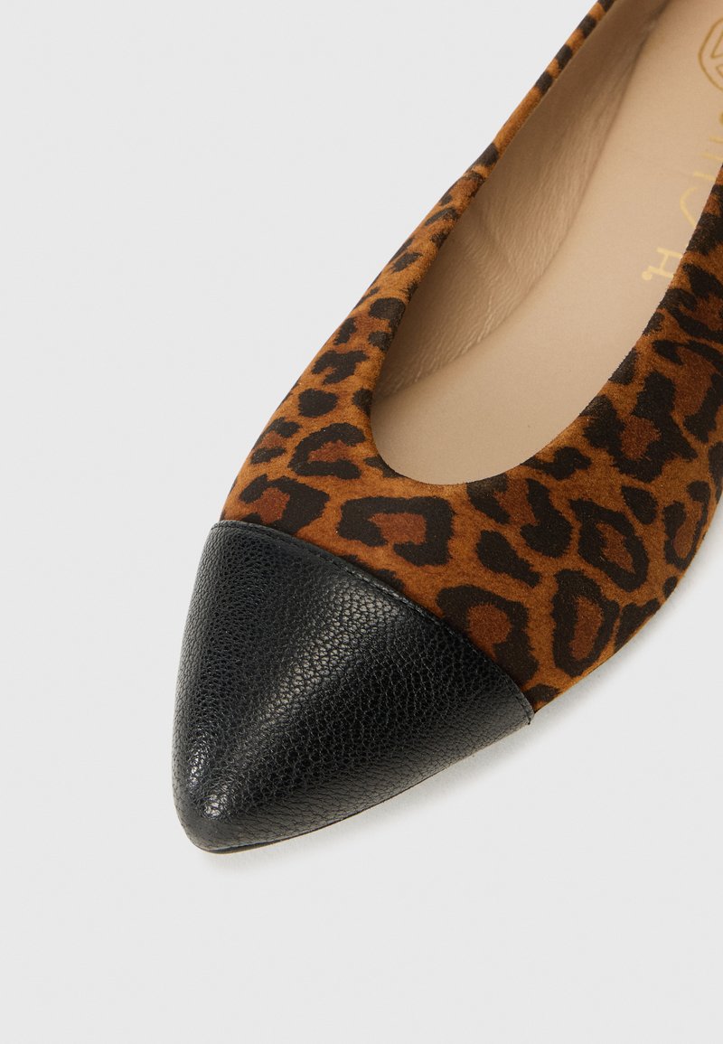 Zapatilla plana con estampado de leopardo que presenta un empeine de ante marrón y una puntera en cuero texturizado negro. Interior suave con un detalle mínimo.