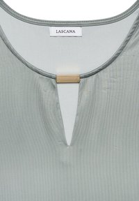 Light green blouse with a round neckline and a small V-cutout at the front. Features a gold-tone rectangular accent. Soft, smooth fabric.