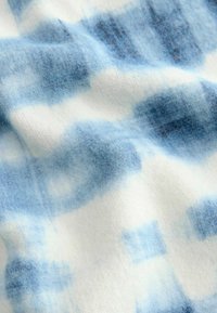 Tissu doux à motifs bleus et blancs avec un effet aquarelle, présentant une texture et des nuances de bleu variées.